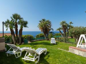three lawn chairs and palm trees and the ocean at Apartment Le Margherite - SLR259 by Interhome in Costarainera +24 photos