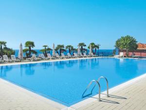 a large swimming pool with chairs and umbrellas at Apartment Le Margherite - SLR259 by Interhome in Costarainera