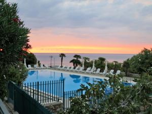 a pool with chairs and a sunset in the background at Apartment Le Margherite - SLR261 by Interhome in Costarainera