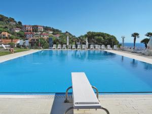 a large swimming pool with a bench in front of it at Apartment Le Margherite - SLR261 by Interhome in Costarainera