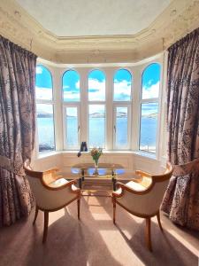 a room with a table and two chairs and windows at Corriemar House in Oban