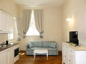 een woonkamer met een blauwe bank en een tv bij Apartment Winery Villa Vitas - App-3 by Interhome in Strassoldo