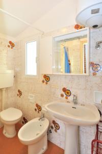 bagno bianco con lavandino e servizi igienici di Holiday Home Cassiopea by Interhome a Bibione