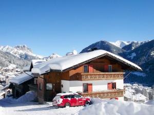 a red car parked in front of a house with snow at Apartment Tieja de Gotart-1 by Interhome in Vigo di Fassa