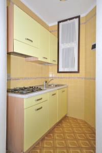 una cucina con armadi gialli e lavandino di Apartment Villaggio Tivoli-3 by Interhome a Bibione