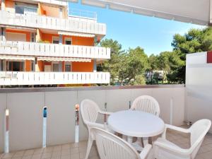 uma varanda com uma mesa e cadeiras brancas e um edifício em Apartment Cavallino by Interhome em Bibione