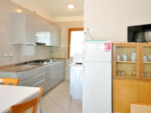 cocina con nevera blanca y mesa en Apartment Villaggio Delfino-2 by Interhome, en Bibione
