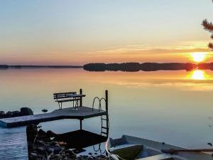 a dock with a bench on the water at sunset at Holiday Home Puolen hehtaarin metsä by Interhome in Haapaniemi