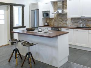 a kitchen with white cabinets and a counter with stools at Holiday Home Kivipirtti by Interhome in Keuruu