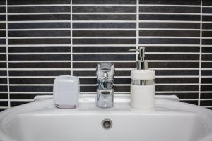 ein Waschbecken mit einem Wasserhahn und zwei Tassen drauf in der Unterkunft Meridian Tower Apartment in Swansea