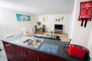 a kitchen with a sink and a living room at Meridian Tower Apartment in Swansea