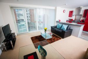 a living room with a black leather couch and a large window at Meridian Tower Apartment in Swansea