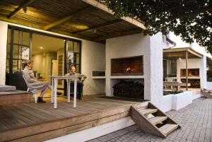 two people sitting at a table on a deck with a fireplace at Oudewerfskloof Olive Farm in Stilbaai