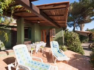 a patio with chairs and tables and a wooden pergola at Holiday Home Piccola Oasi-3 by Interhome in Capoliveri