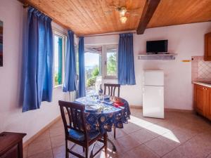 a dining room with a table and a kitchen with blue curtains at Holiday Home Piccola Oasi 9 by Interhome in Capoliveri +32 photos
