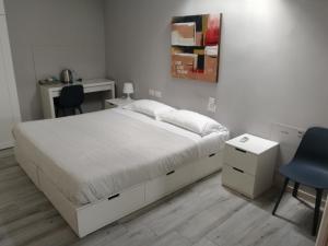 Schlafzimmer mit einem weißen Bett, einem Schreibtisch und Stühlen in der Unterkunft BGY Airport House Grassobbio in Grassobbio