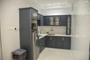 巴勒如拉斯غيوم للفلل الفندقية的厨房配有黑色橱柜和不锈钢冰箱