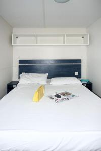 a bed with a book and magazines on it at Holiday Home Residence Village-1 by Interhome in Cavallino-Treporti