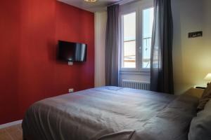 - une chambre avec un lit et une télévision sur un mur rouge dans l'établissement Casa del Sole by Studio Vita, à Bologne