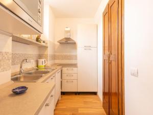 a white kitchen with a sink and a counter at Apartment Glicine by Interhome in Perledo