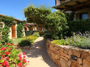 un jardín con flores y una pared de piedra en Holiday Home Acacia 3 - Vista Village by Interhome, en Porto San Paolo
