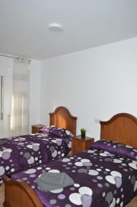 a bedroom with two beds with purple and white covers at El mirador de Noemí in Gijón