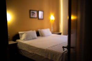 a bedroom with a bed with white sheets and pillows at Hotel Pelops in Olympia