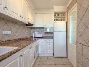 a kitchen with white cabinets and a white refrigerator at Apartment Alqueria Sol by Interhome in Denia +11 photos