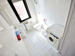 a white bathroom with a toilet and a sink at Apartment Vistamare by Interhome in San Silvestro +3 photos