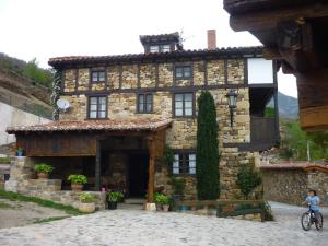 a stone house with a person riding a bike in front at Posada Torcaz in Cahecho
