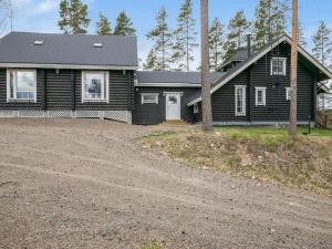 a black house with a gravel driveway in front of it at Holiday Home Le club 44 by Interhome in Kausala