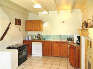 La cuisine est équipée de placards en bois et d'un four avec plaques de cuisson. dans l'établissement Holiday Home Gîte des Oiseaux by Interhome, à Plouha