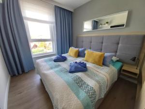 a bedroom with a bed with blue pillows and a window at Bel Mare Sztorm in Międzyzdroje