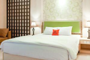 库塔KoolKost at Bypass Jimbaran - Minimum Stay 30 Nights的卧室里有一张白色的大床，上面有一个红色的枕头