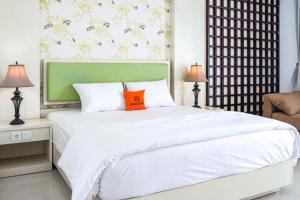 库塔KoolKost at Bypass Jimbaran - Minimum Stay 30 Nights的卧室配有一张带橙色枕头的大型白色床。
