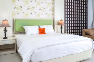 a bedroom with a large white bed with an orange pillow at KoolKost @ Bypass Jimbaran in Kuta
