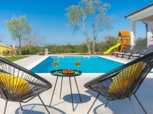 dos sillas y una mesa con dos copas de vino en Holiday Home Villa Veli vrt by Interhome en Žminj