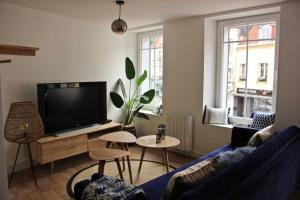 een woonkamer met een blauwe bank en een tv bij A stylish apartment in the centre of town in Montreuil-sur-Mer