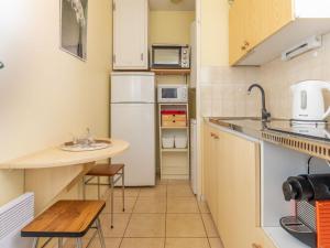 Elle comprend une petite cuisine équipée d'un réfrigérateur blanc et d'une table. dans l'établissement Apartment Plein Soleil-2 by Interhome, à Arcachon