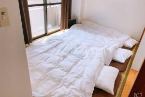 a bed with white sheets and pillows in a room at Esperanza 204号室 in Tokyo