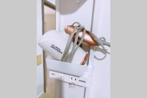 a white hair dryer hanging from a wall at Esperanza 204号室 in Tokyo