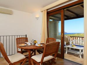 a dining room with a table and chairs and a balcony at Holiday Home Corbezzolo 9 - Vista Village by Interhome in Porto San Paolo
