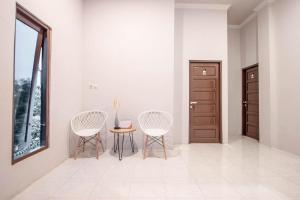 duas cadeiras e uma mesa num quarto com uma porta em Krisan Guest House Syariah Mitra RedDoorz em Banjarbaru