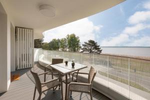 a table and chairs on a balcony with a view of the water at Rogowo Pearl Exclusive Apartments by Renters in Rogowo