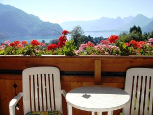 two chairs and flowers on a balcony with a view at Frühstückspension Seeblick in Sankt Gilgen
