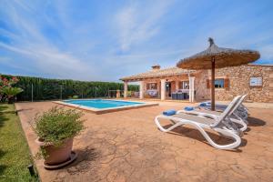 a villa with a pool and two lounge chairs and an umbrella at Can grau petit in Sencelles