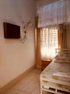 1 dormitorio con 1 cama y TV en la pared en WEST ORANGE LODGE, en Moshi