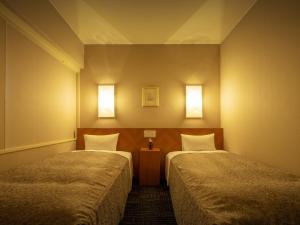 a room with two beds and two lights on the wall at Hotel Ace Morioka in Morioka