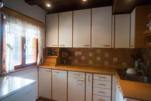 cocina con armarios blancos, fregadero y ventana en Cottage in the woods - Lake Bohinj en Bohinj