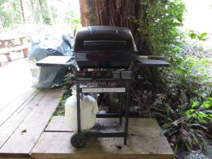 a grill sitting on a stand on a wooden deck at C&N Backpackers - Ucluelet in Ucluelet